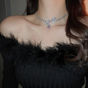 Close-up of sparkling zircon bow and teardrop pendant necklace worn on neck