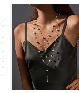 Detail of elegant S925 silver layered necklace with white pearls and long Y-shaped chain