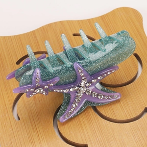 Detail of blue starfish hair claw clip featuring purple rhinestones and glitter resin texture
