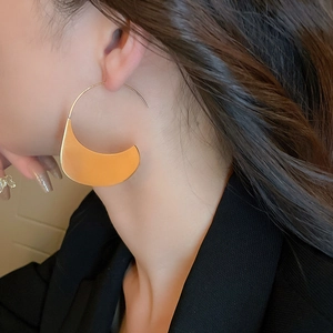 Gros plan de boucles d'oreilles lune dorées sur un mannequin à l'éclat métal