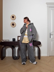 Détail de survêtement rétro gris foncé avec lettrage rose et jaune dans un décor intérieur