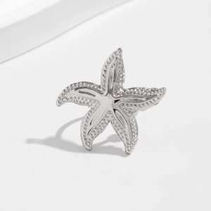 Macro detail of silver starfish ring featuring polished metal and textured edges
