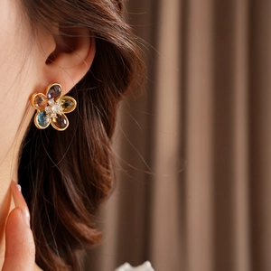 Close-up of flower stud earrings with colorful gemstones and gold plating on a model