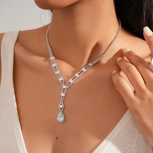 Macro shot of silver teardrop V-shaped rhinestone necklace on a model's neck