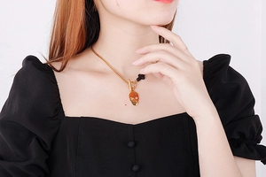 Close-up of gold skull and cross pendant necklace with OT buckle on male model