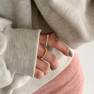 Close-up of minimalist 925 silver beaded rings styled in gold and silver layers