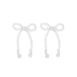 Detail view of handcrafted white beaded bow earrings with elegant pearl accents