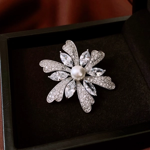 Macro shot of silver floral brooch with white pearl and sparkling zircon in a black box