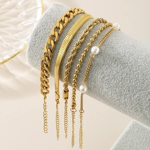 Close-up of a 5-piece gold bracelet set with snake, twist, and pearl chain details