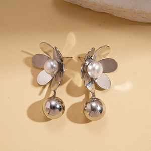 Close-up of silver flower earrings with pearl centers and dangling metal spheres