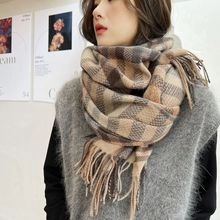 Close-up of khaki and dark brown checkered scarf with soft tassel detail on woman