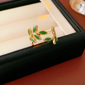Detail of leaf ring in gold finish with green enamel on a white jewelry cushion