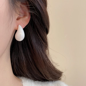 Close-up of a model wearing a polished white acrylic water drop earring for a sleek look
