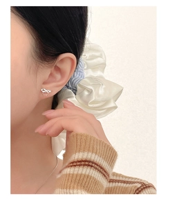 Close-up of elegant S999 sterling silver bow earrings worn on a female model's ear