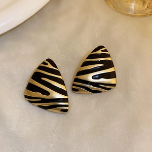 Macro shot of triangle zebra pattern earrings with black and gold enamel finish