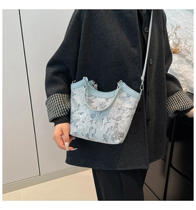 Detail of light blue embroidered handbag styled with a grey coat on a female model