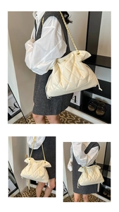 Detail of cream quilted tote bag with golden chain strap and drawstring closure