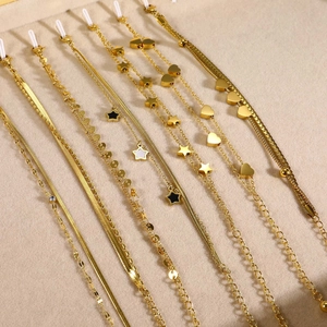 Gold stainless steel layered bracelets with zircon hearts and snake chains on beige display