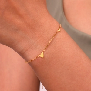 Gold stainless steel chain bracelet with small heart charms worn on a female wrist