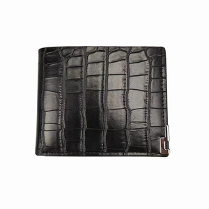 Detailed close-up of black crocodile embossed leather texture on men's wallet with silver metal