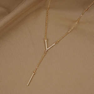 Long gold Y-shaped necklace with V-pendant and vertical bar on soft beige fabric background
