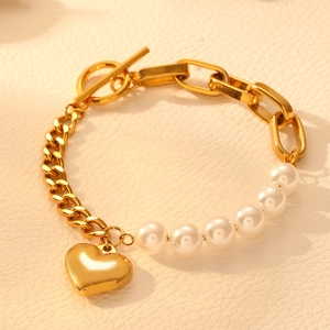 Golden heart charm bracelet with pearls and OT buckle on leather background