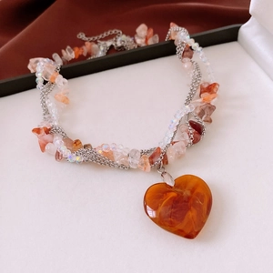 Detail of multi-layer beaded necklace with large amber resin heart pendant and silver chains