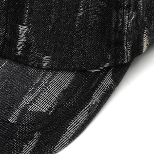 Macro shot of distressed black denim baseball cap with vintage frayed fabric details