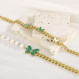 Detailed view of vintage gold chain bracelet with green enamel butterfly and pearls