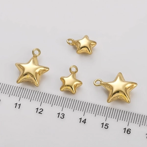 Four 14K gold filled star pendants in different sizes shown with a ruler for scale