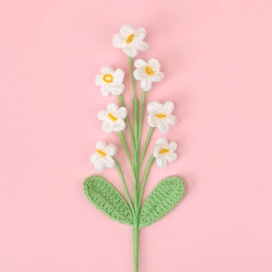Detailed view of handmade crochet lily of the valley with white petals on pink backdrop
