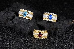 Detailed macro view of vintage gold hollow rings with garnet and topaz on black stones
