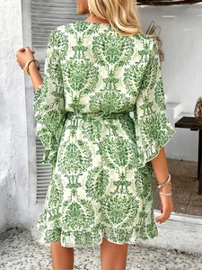 Back view of short floral chiffon dress with green pattern and waist tie detail
