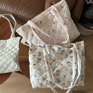 Quilted tote bags with floral and cartoon prints on a wooden table in a warm home setting