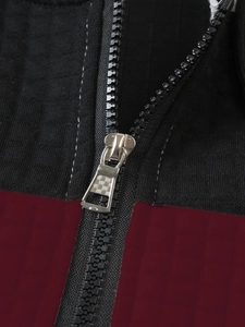 Detail of silver metal zipper pull on burgundy and black textured checkered hoodie fabric