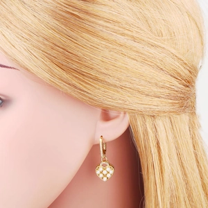 Elegant gold heart earrings with white pearls and sparkling zircons shown on model