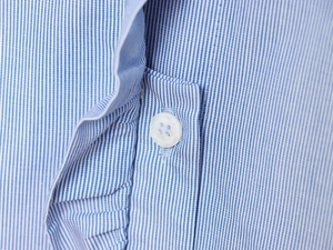 Detailed close-up of blue and white striped poplin fabric with white buttons on the shirt