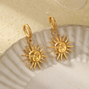 Boucles d'oreilles soleil dorées avec anneaux polis et pendentifs visage sculpté