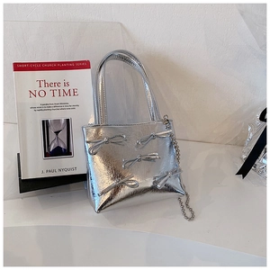 Close-up of silver metallic handbag with bow accents and chain strap detail