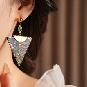 Close-up of vintage triangle drop earrings with green beads on a female model