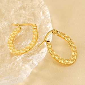 Gold plated oval hoop earrings with hammered texture on a champagne velvet background
