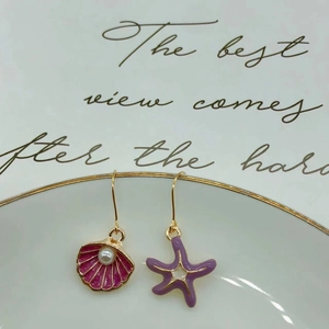 Detail of asymmetrical ocean earrings with pink seashell, purple starfish and white pearls