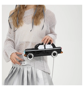 Close-up of a creative car-shaped crossbody bag featuring glossy black patent leather detail