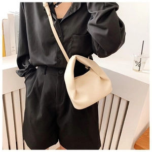 Close-up of creamy white pleated cloud bag with litchi texture on black shirt