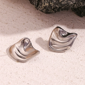 Macro shot of silver irregular geometric wave stud earrings on a textured stone surface