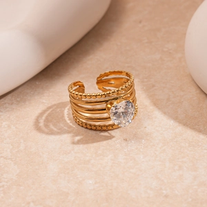 Macro shot of gold layered ring with heart zircon stone on warm stone background