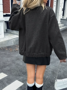 Street style view of a dark grey oversized knitted vest paired with a leather skirt