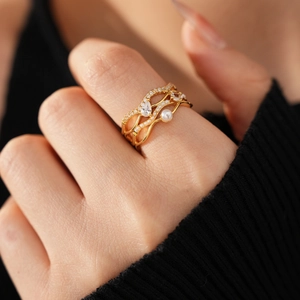 Makroaufnahme von 18k vergoldetem Mehrschichtring mit Zirkon-Tropfen und weißer Perle
