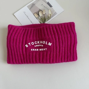 Detailaufnahme des rosaroten Strickstirnbands mit weißem Stockholm Sweden Schriftzug und Textur