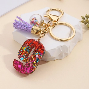 Detail of glitter resin number 9 keychain with purple tassel and star ball pendant